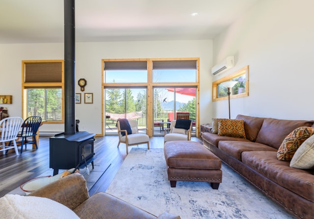 living area with a wood stove, wood finished floors, plenty of natural light, and an AC wall unit