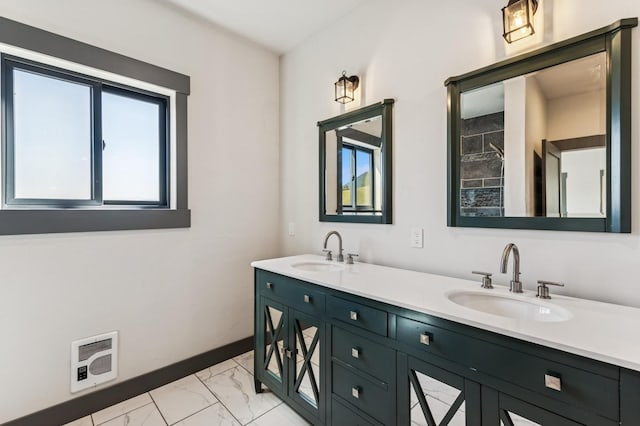 bathroom with marble finish floor, double vanity, a sink, and heating unit