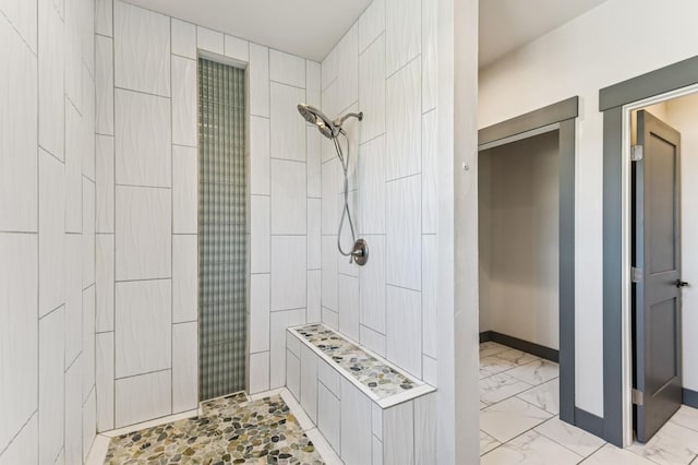 full bathroom featuring baseboards, marble finish floor, and tiled shower