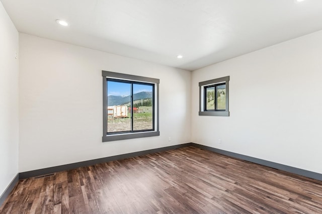 empty room with baseboards, dark wood-style floors, and recessed lighting