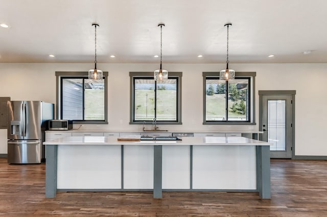 kitchen featuring stainless steel appliances, pendant lighting, dark wood-type flooring, light countertops, and recessed lighting