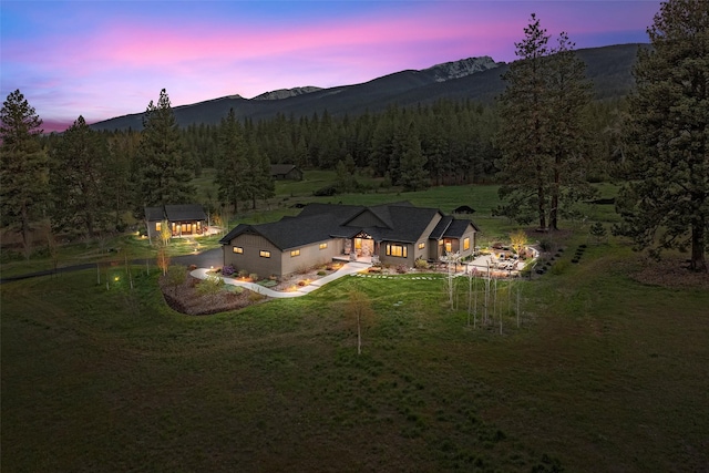 aerial view at dusk featuring a mountain view and a view of trees