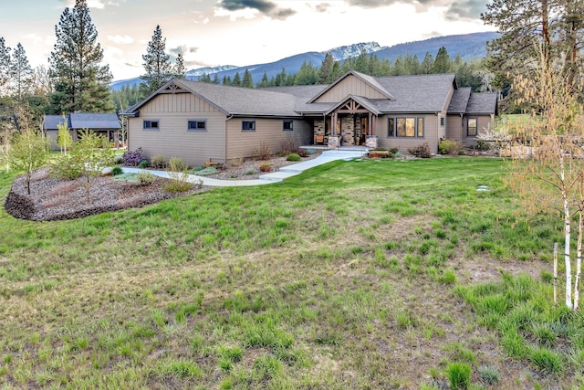 ranch-style home with covered porch, a mountain view, a front lawn, board and batten siding, and a shingled roof