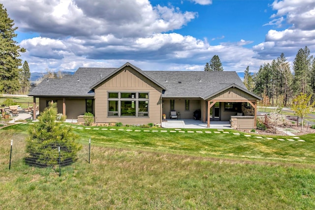 rear view of property with a yard, roof with shingles, a patio area, and board and batten siding