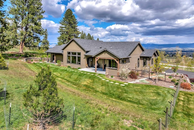 rear view of property with a patio area, roof with shingles, fence, and a lawn