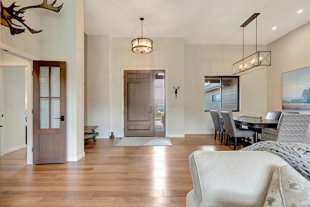 entrance foyer with light wood-type flooring, a chandelier, and a high ceiling