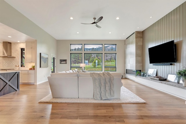 living room with light wood-style flooring, baseboards, a ceiling fan, and recessed lighting
