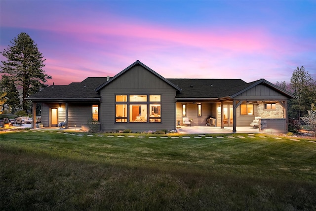 back of house featuring a yard, board and batten siding, a patio area, and roof with shingles