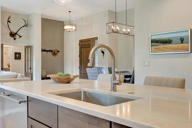 kitchen with hanging light fixtures, a sink, open floor plan, a notable chandelier, and light countertops
