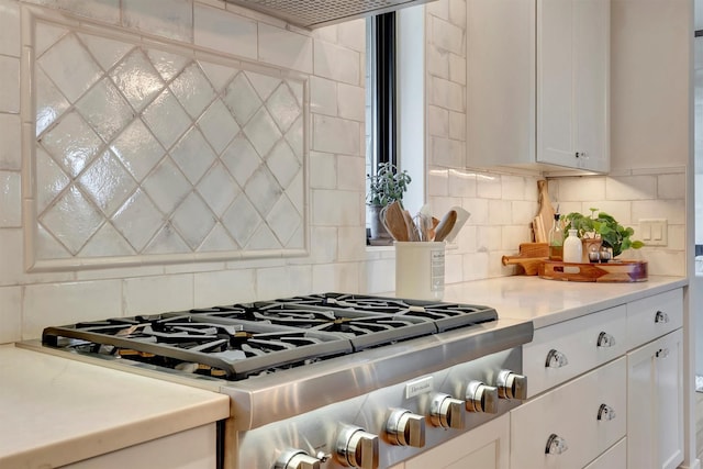 kitchen with white cabinetry, light countertops, stainless steel gas cooktop, and backsplash