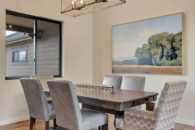 dining room with an inviting chandelier, baseboards, and wood finished floors