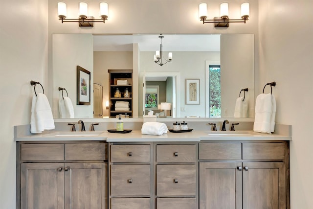 bathroom featuring double vanity, a chandelier, and a sink