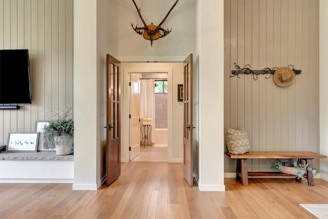 mudroom featuring light wood-style flooring, baseboards, and wood walls