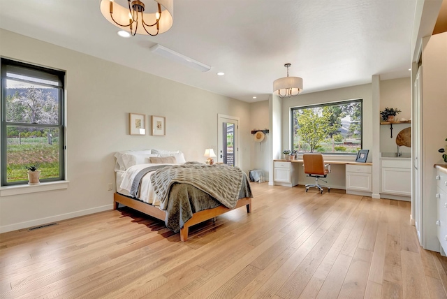 bedroom with light wood-style flooring, baseboards, visible vents, built in study area, and a chandelier