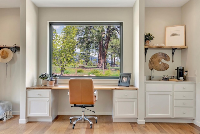office area featuring built in desk, light wood-style flooring, and a wealth of natural light