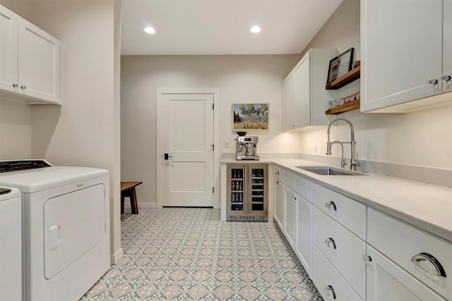 clothes washing area with light floors, washing machine and dryer, beverage cooler, a sink, and cabinet space
