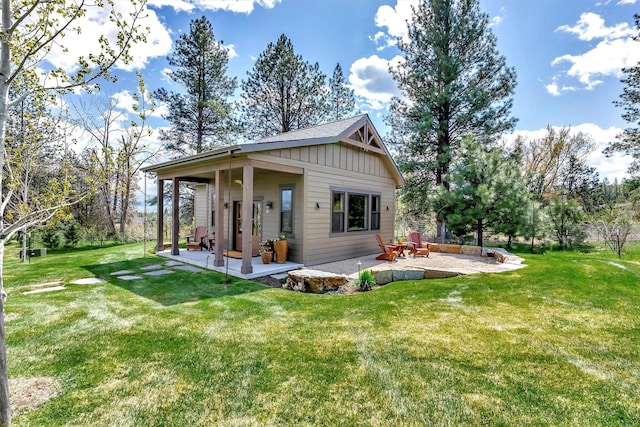 rear view of property featuring a yard, a patio area, and board and batten siding