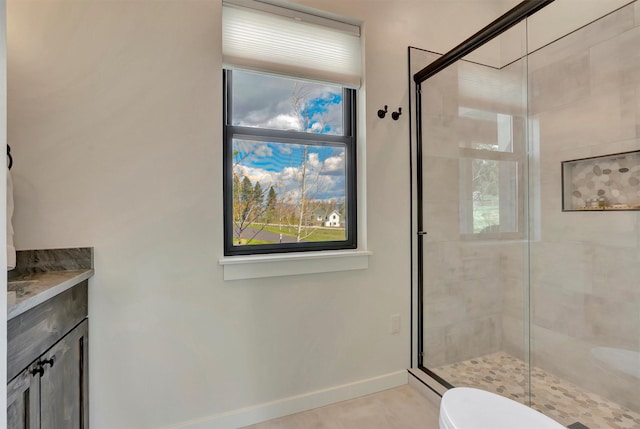 bathroom featuring vanity, toilet, baseboards, and a stall shower