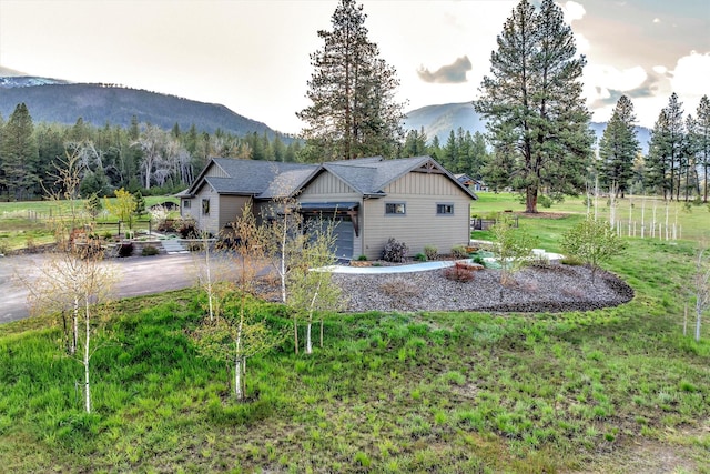 exterior space with a lawn, board and batten siding, driveway, a mountain view, and an attached garage