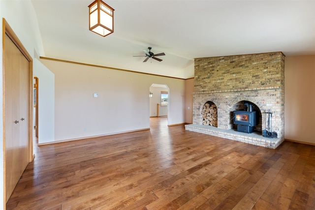6280 Alamosa Ln, Bozeman, MT 59718 - unfurnished living room featuring a ceiling fan, lofted ceiling, wood finished floors, arched walkways, and a wood stove