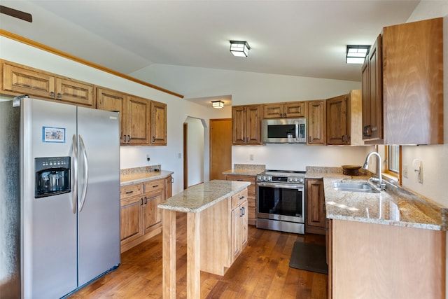 6280 Alamosa Ln, Bozeman, MT 59718 - kitchen featuring brown cabinetry, a sink, vaulted ceiling, appliances with stainless steel finishes, and dark wood-style floors