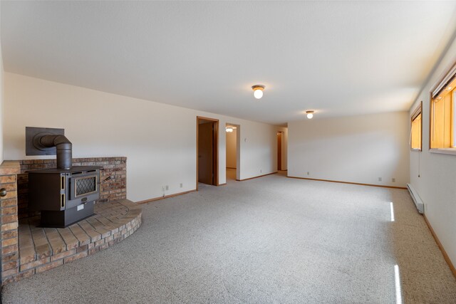 6280 Alamosa Ln, Bozeman, MT 59718 - unfurnished living room with baseboards, a wood stove, baseboard heating, and carpet flooring