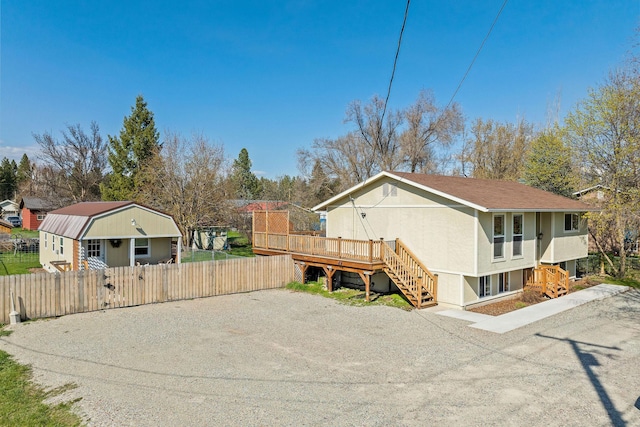 view of side of property with fence, gravel driveway, a deck, stairway, and a gate