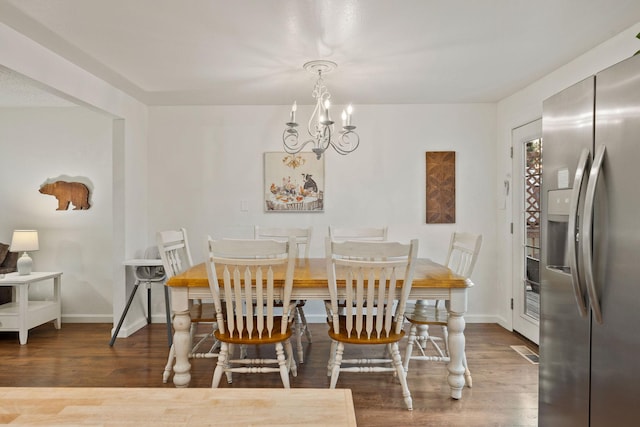 dining space with baseboards, a notable chandelier, and wood finished floors