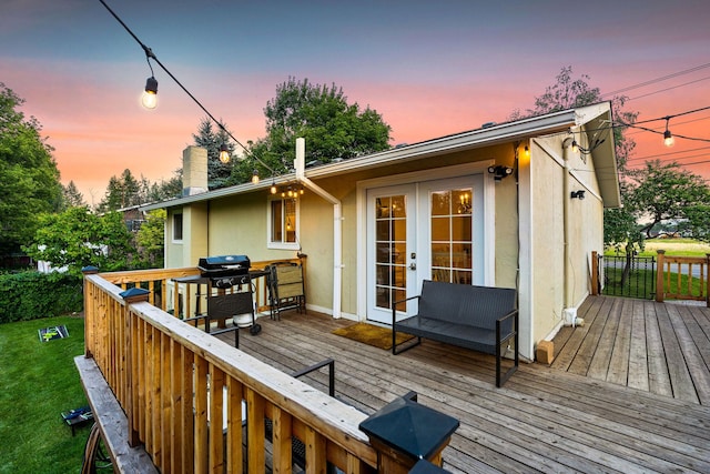 wooden terrace featuring a yard, a grill, and french doors