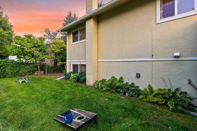 view of property exterior featuring a chimney and a lawn