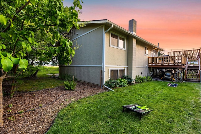 rear view of house featuring a lawn, a chimney, fence, and a wooden deck