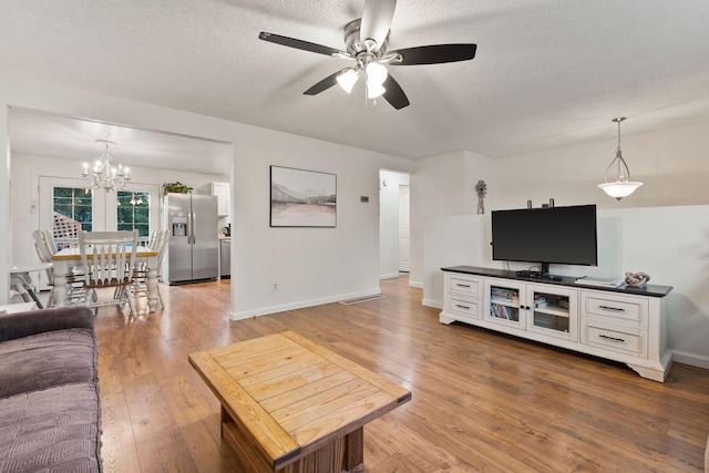 living area with a textured ceiling, baseboards, wood finished floors, and ceiling fan with notable chandelier