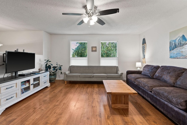 living room featuring a textured ceiling, baseboards, a ceiling fan, and wood finished floors