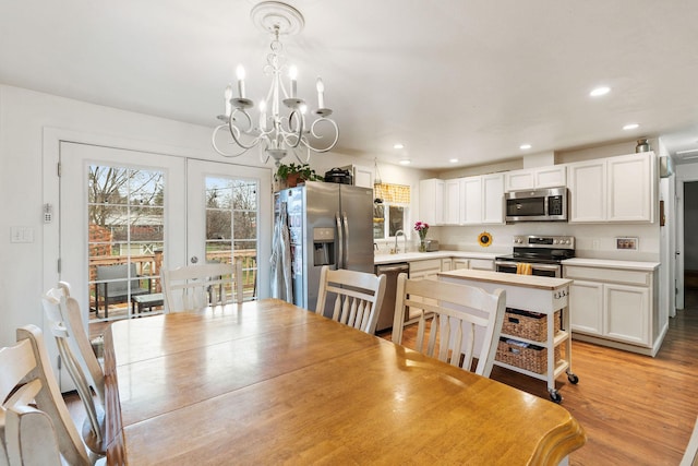 dining space featuring french doors, light wood finished floors, a chandelier, and recessed lighting