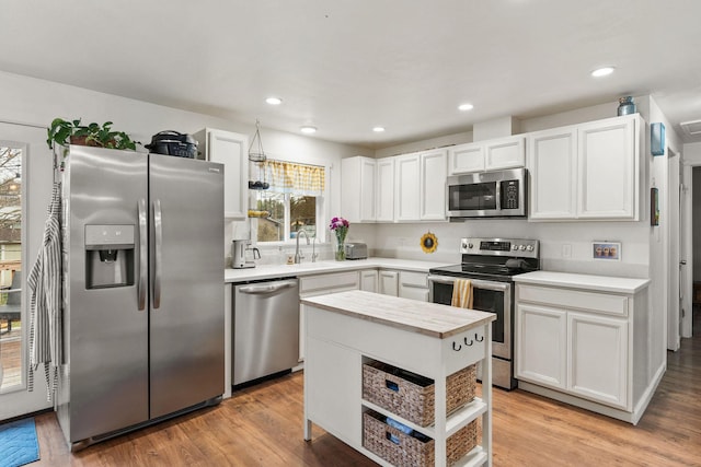kitchen featuring a sink, appliances with stainless steel finishes, light countertops, white cabinets, and light wood-style floors
