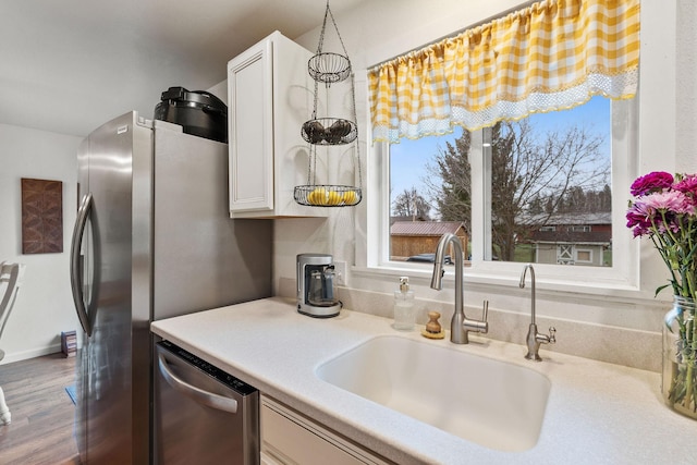 kitchen featuring white cabinetry, light countertops, stainless steel appliances, and a sink