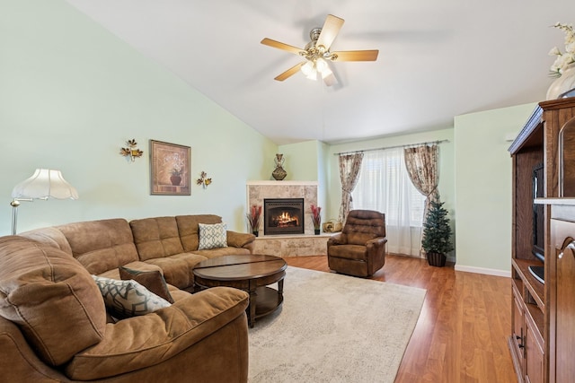 living area with lofted ceiling, a ceiling fan, baseboards, light wood finished floors, and a fireplace