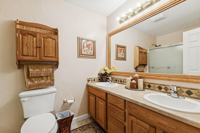bathroom featuring toilet, an enclosed shower, double vanity, and a sink