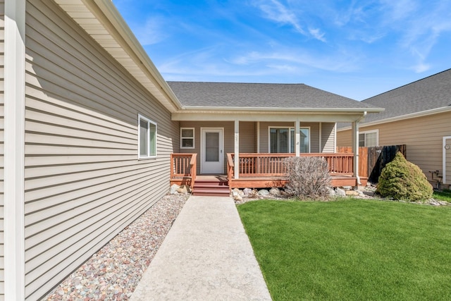 entrance to property featuring a shingled roof and a lawn