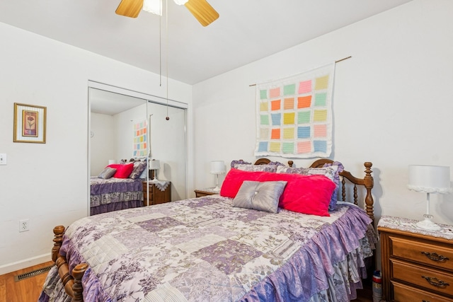 bedroom with a closet, wood finished floors, visible vents, a ceiling fan, and baseboards