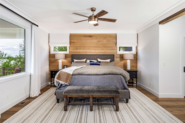 bedroom with baseboards, wooden walls, ceiling fan, and wood finished floors