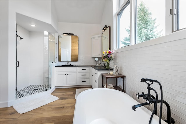 full bathroom with a shower stall, a soaking tub, vanity, decorative backsplash, and wood finished floors