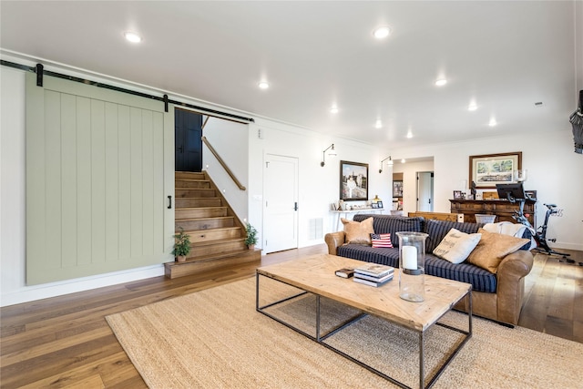 living room featuring stairs, wood finished floors, ornamental molding, a barn door, and visible vents