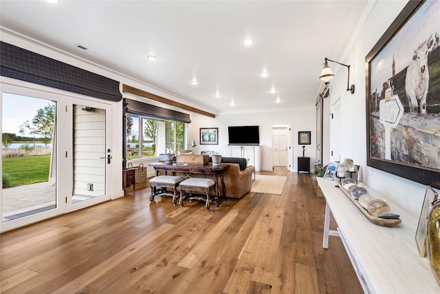 living area featuring ornamental molding, a barn door, light wood-type flooring, visible vents, and recessed lighting