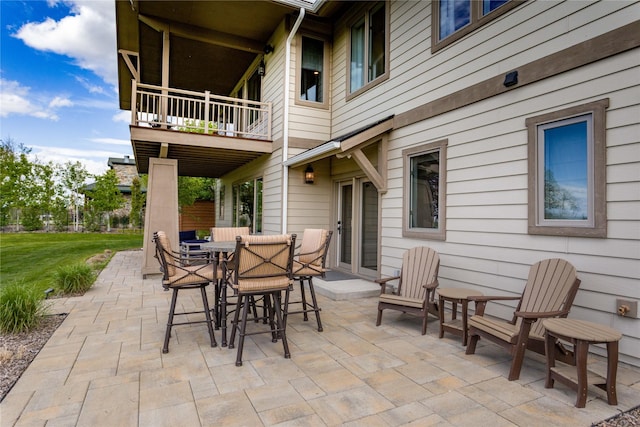view of patio with a balcony and outdoor dining space