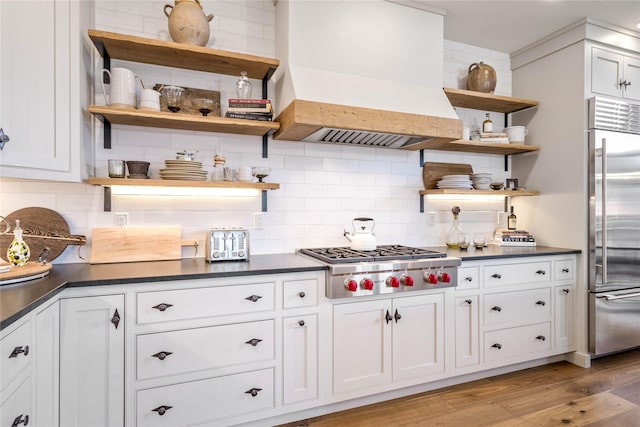 kitchen featuring open shelves, dark countertops, stainless steel appliances, and custom exhaust hood