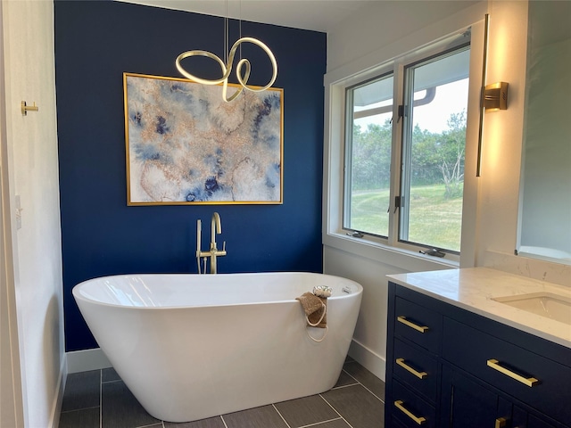 full bath with tile patterned floors, baseboards, a freestanding bath, and an inviting chandelier
