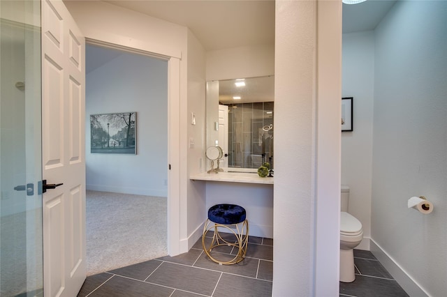 bathroom with toilet, tile patterned flooring, baseboards, and a shower with shower door