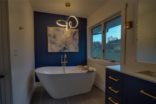 full bath featuring vanity, tile patterned flooring, baseboards, and a freestanding tub