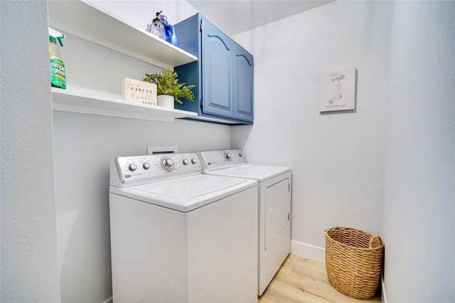 laundry room with baseboards, light wood-style flooring, washer and dryer, and cabinet space